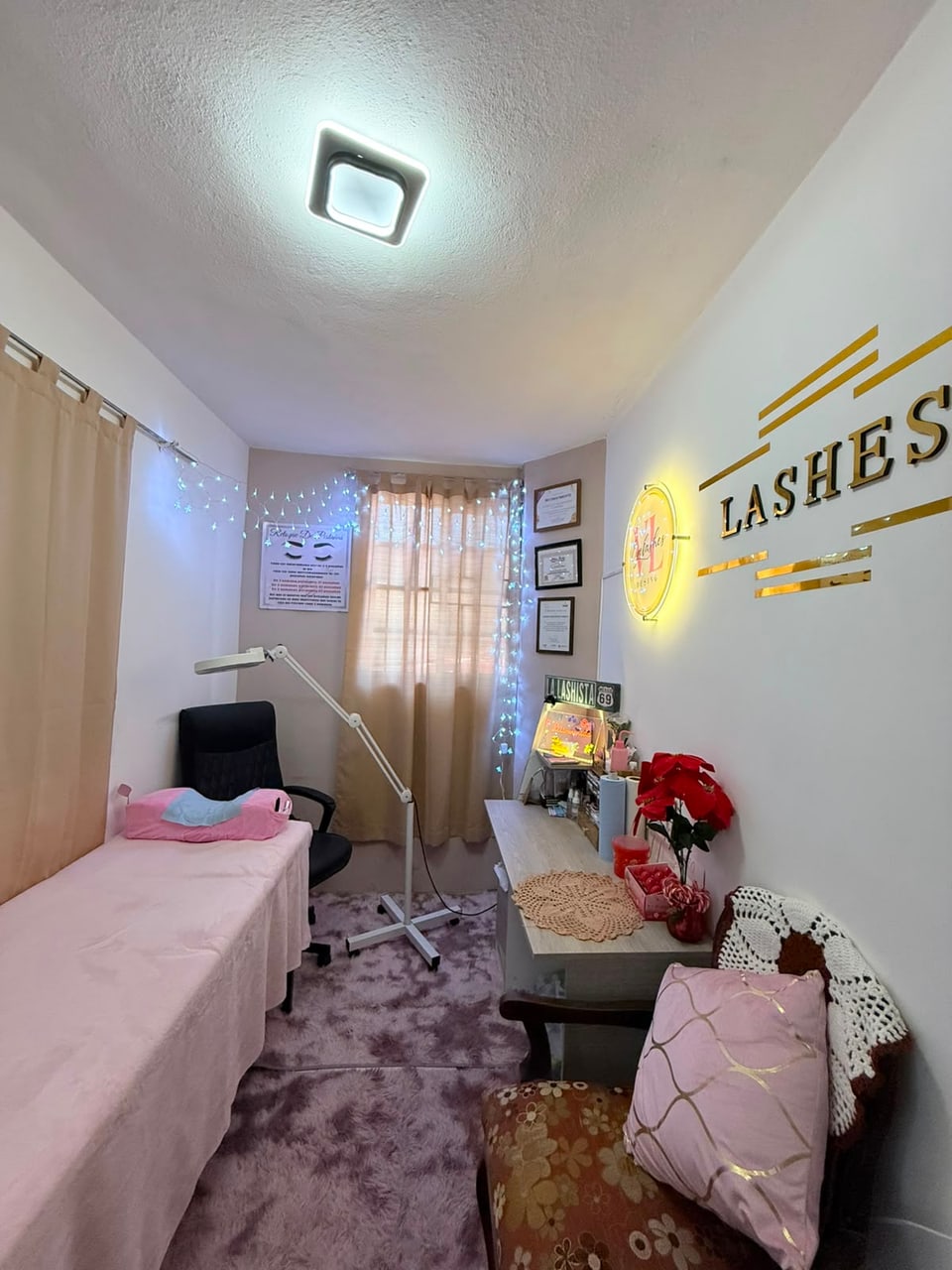 Estudio VL con camilla rosa, lámpara de trabajo y letrero en la pared
